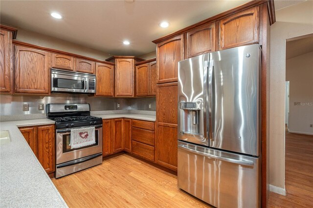 409 San Jose Dr, Winter Haven, FL 33884 - kitchen featuring appliances with stainless steel finishes, light countertops, brown cabinetry, light wood-style flooring, and recessed lighting
