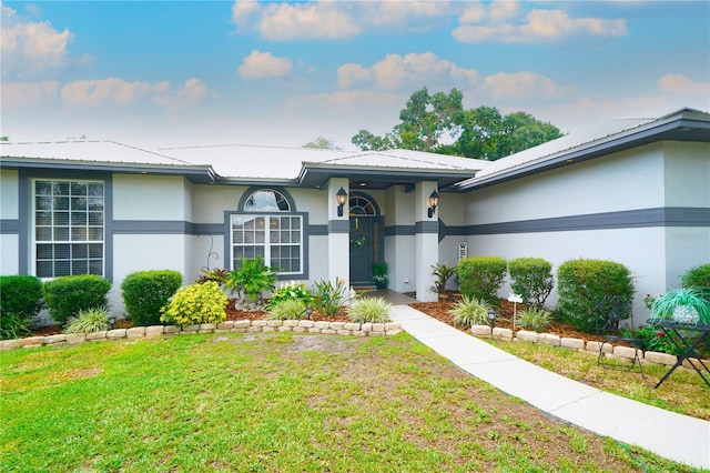 8760 Plantation Ridge Blvd, Lakeland, FL 33809 - doorway to property with stucco siding, a yard, and metal roof