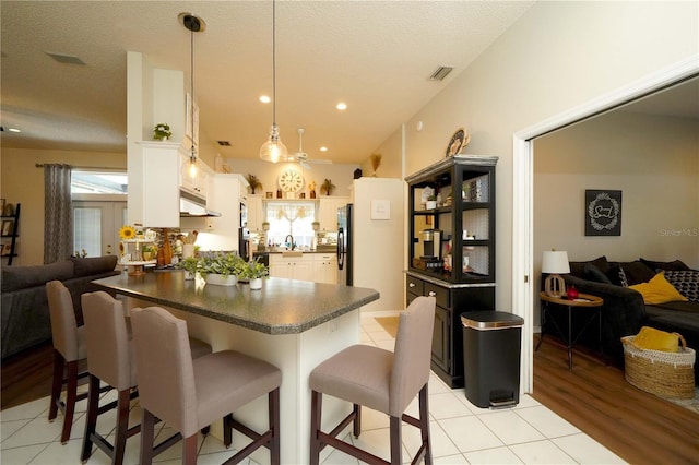 8760 Plantation Ridge Blvd, Lakeland, FL 33809 - kitchen featuring dark countertops, open floor plan, light tile patterned flooring, a breakfast bar, and a textured ceiling