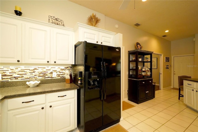 8760 Plantation Ridge Blvd, Lakeland, FL 33809 - kitchen featuring black fridge, dark countertops, decorative backsplash, light tile patterned flooring, and white cabinets