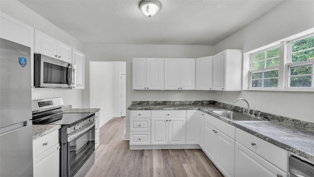 725 Ave B SW, Winter Haven, FL 33880 - kitchen with appliances with stainless steel finishes, a sink, white cabinets, light wood-style flooring, and a textured ceiling