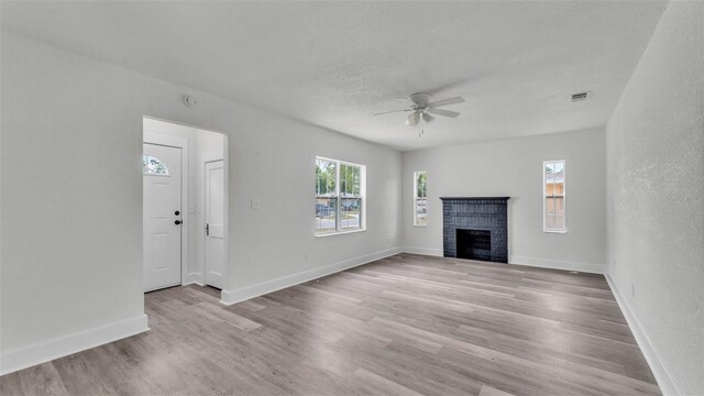 725 Ave B SW, Winter Haven, FL 33880 - unfurnished living room with light wood-style flooring, ceiling fan, a brick fireplace, and baseboards