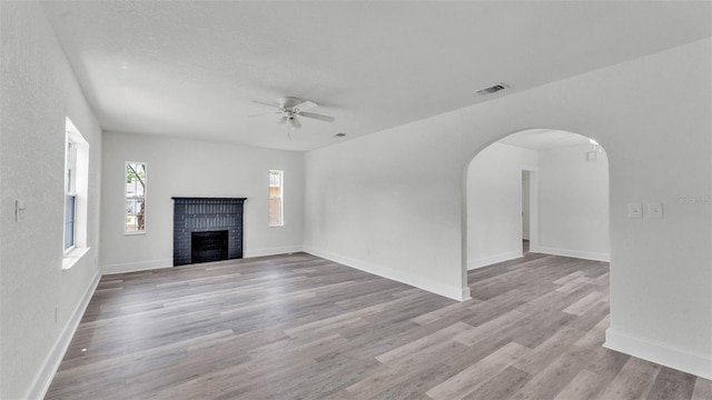 725 Ave B SW, Winter Haven, FL 33880 - unfurnished living room featuring a ceiling fan, arched walkways, a fireplace, wood finished floors, and baseboards