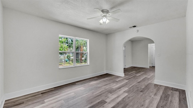 725 Ave B SW, Winter Haven, FL 33880 - spare room featuring arched walkways, a ceiling fan, wood finished floors, baseboards, and a textured ceiling