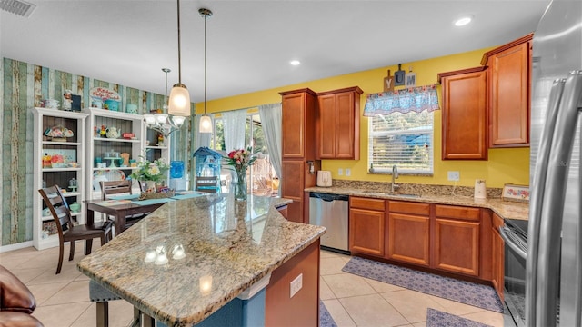 6435 Sedgeford Dr, Lakeland, FL 33811 - kitchen with appliances with stainless steel finishes, a sink, a kitchen island, light stone countertops, and brown cabinetry