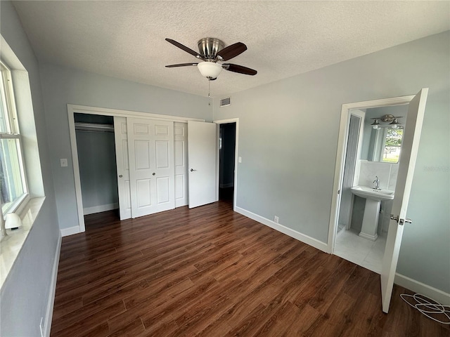 1328 Edgewater Beach Dr, Lakeland, FL 33805 - unfurnished bedroom featuring wood finished floors, a closet, a textured ceiling, baseboards, and ensuite bath