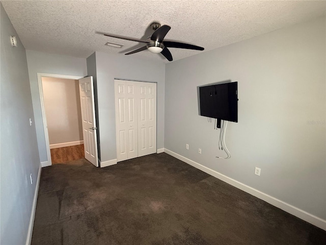 1328 Edgewater Beach Dr, Lakeland, FL 33805 - unfurnished bedroom with a closet, baseboards, a textured ceiling, dark colored carpet, and ceiling fan