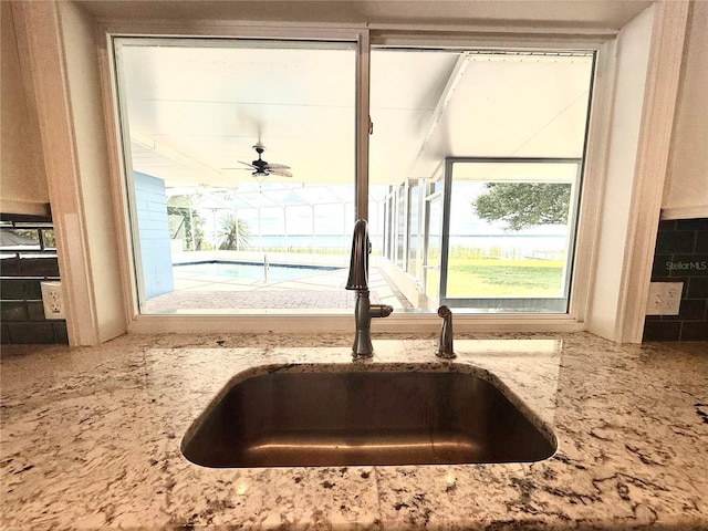 1328 Edgewater Beach Dr, Lakeland, FL 33805 - kitchen view of a sink, light stone countertops, a ceiling fan, and backsplash