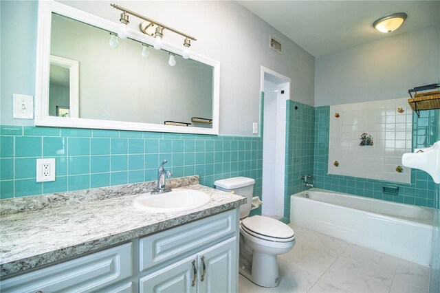 1328 Edgewater Beach Dr, Lakeland, FL 33805 - full bathroom featuring tile walls, a tub to relax in, vanity, marble finish floors, and a wainscoted wall