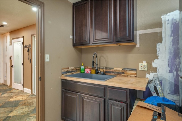 2219 New Jersey Rd, Lakeland, FL 33803 - kitchen with a sink, dark brown cabinetry, wooden counters, stone finish flooring, and recessed lighting