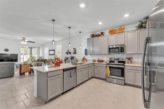 280 Pershing St, Bartow, FL 33830 - kitchen with stainless steel appliances, gray cabinetry, a peninsula, open floor plan, and a ceiling fan