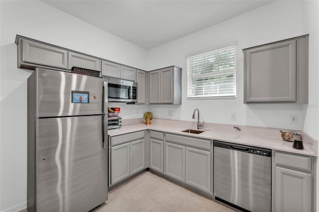 280 Pershing St, Bartow, FL 33830 - kitchen with stainless steel appliances, gray cabinetry, a sink, light countertops, and light tile patterned floors