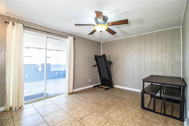 unfurnished room with a ceiling fan, wood walls, and baseboards