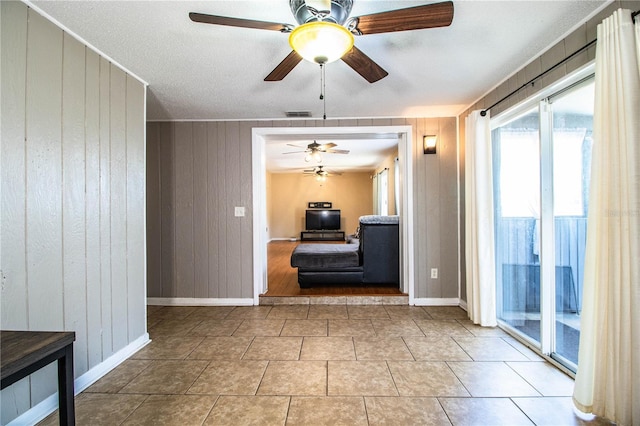 unfurnished room with ceiling fan, wooden walls, and baseboards
