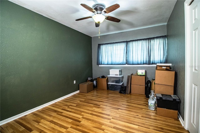 interior space featuring wood finished floors, a ceiling fan, and baseboards