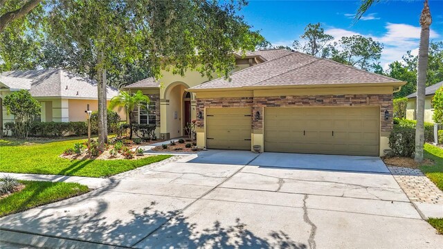 3620 Cordgrass Dr, Valrico, FL 33596 - view of front of property with a garage, driveway, stucco siding, and stone siding