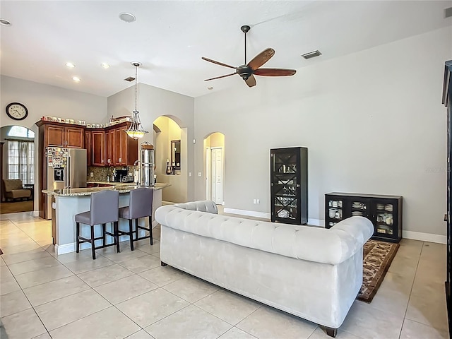 3620 Cordgrass Dr, Valrico, FL 33596 - living room featuring arched walkways, a ceiling fan, light tile patterned flooring, high vaulted ceiling, and baseboards