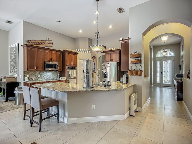 3620 Cordgrass Dr, Valrico, FL 33596 - kitchen featuring stainless steel appliances, arched walkways, light stone countertops, a peninsula, and pendant lighting