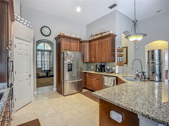 3620 Cordgrass Dr, Valrico, FL 33596 - kitchen with appliances with stainless steel finishes, a sink, arched walkways, light tile patterned flooring, and light stone counters