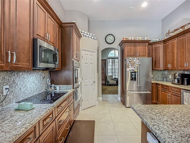 3620 Cordgrass Dr, Valrico, FL 33596 - kitchen with stainless steel appliances, arched walkways, light tile patterned floors, light stone countertops, and backsplash