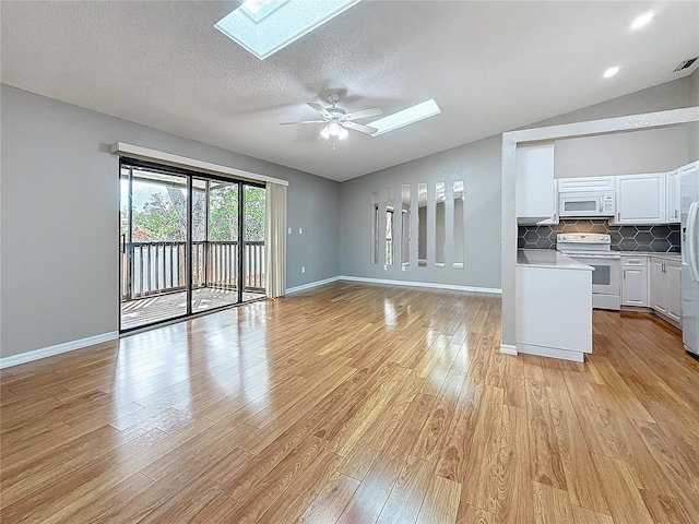 6350 92nd Pl N Unit 2206, Pinellas Park, FL 33782 - unfurnished living room featuring a skylight, lofted ceiling, light wood-style flooring, ceiling fan, and baseboards