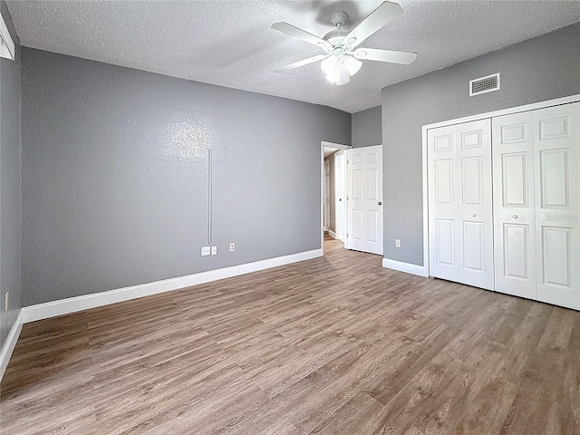 6350 92nd Pl N Unit 2206, Pinellas Park, FL 33782 - unfurnished bedroom with a textured ceiling, wood finished floors, baseboards, a closet, and a textured wall