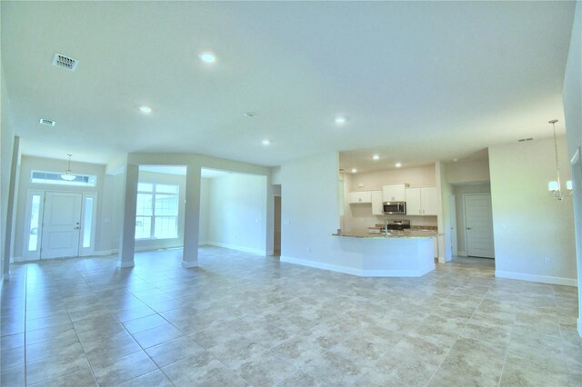 unfurnished living room with recessed lighting, baseboards, a chandelier, and light tile patterned flooring