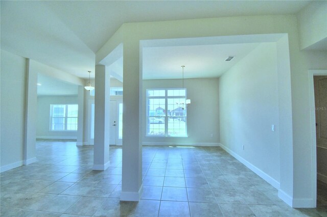 spare room featuring a chandelier, light tile patterned flooring, and baseboards