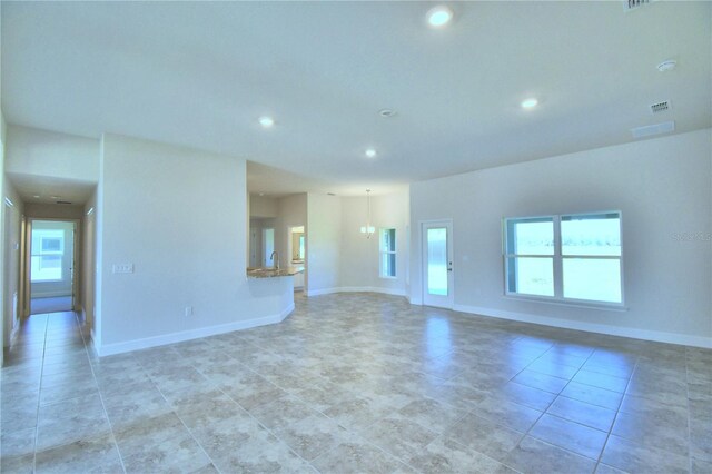 unfurnished living room with healthy amount of natural light, recessed lighting, baseboards, and light tile patterned flooring