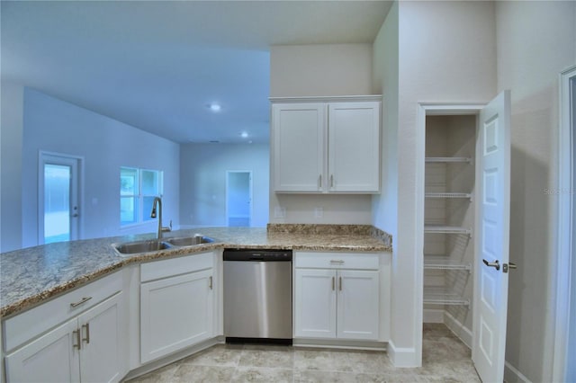 kitchen with stainless steel dishwasher, a sink, light stone countertops, and white cabinets