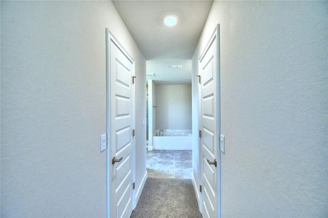 hallway with a textured wall and dark carpet