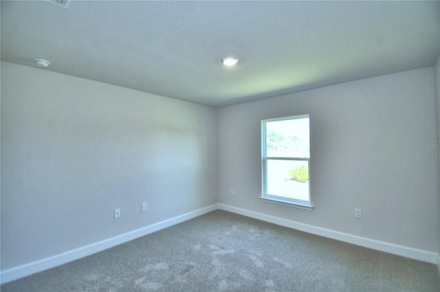 unfurnished room with dark colored carpet, baseboards, and a smoke detector