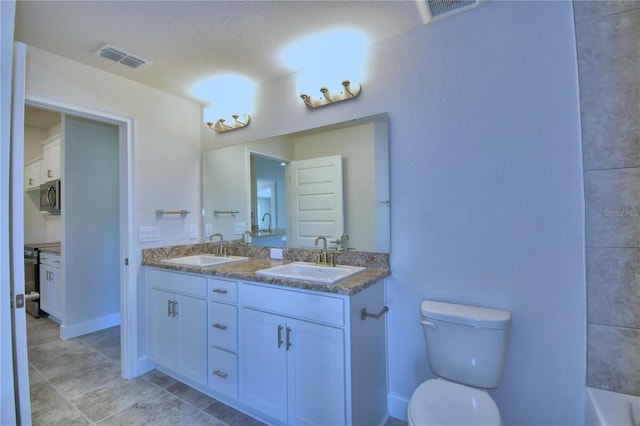 full bath featuring toilet, double vanity, a tub, and baseboards