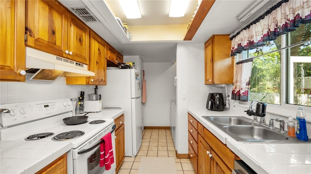 417 Yolonda Ct, Lakeland, FL 33809 - kitchen featuring white appliances, under cabinet range hood, a sink, tile counters, and decorative backsplash