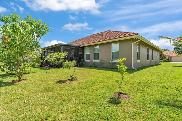 5033 Sugar Bay St, Sebring, FL 33872 - back of property with stucco siding, a yard, a sunroom, and a tiled roof
