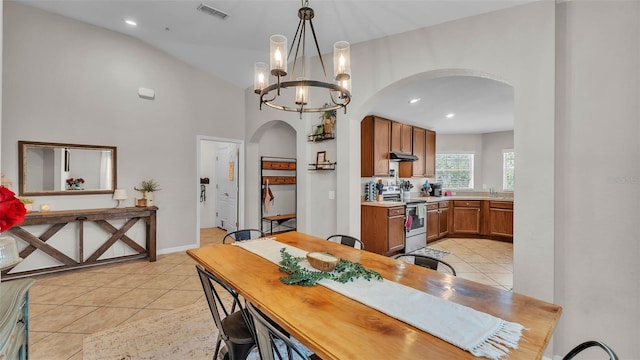 dining space with arched walkways, light tile patterned floors, a chandelier, recessed lighting, and high vaulted ceiling