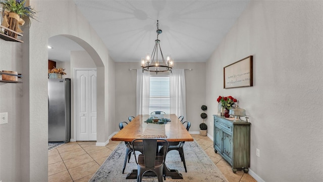dining room with arched walkways, light tile patterned floors, a chandelier, baseboards, and a textured wall