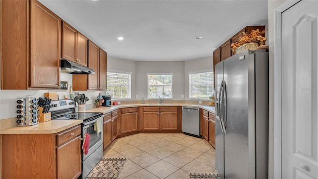 kitchen featuring stainless steel appliances, under cabinet range hood, a sink, plenty of natural light, and recessed lighting