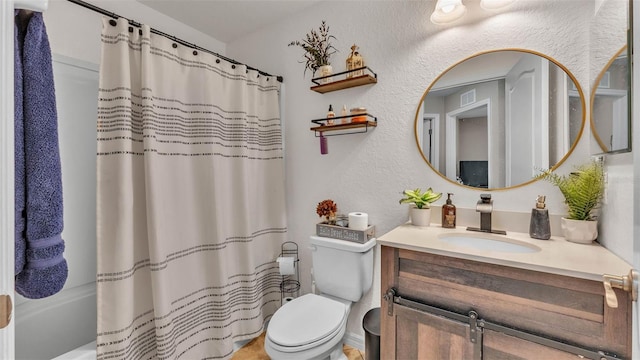bathroom with a textured wall, vanity, and toilet