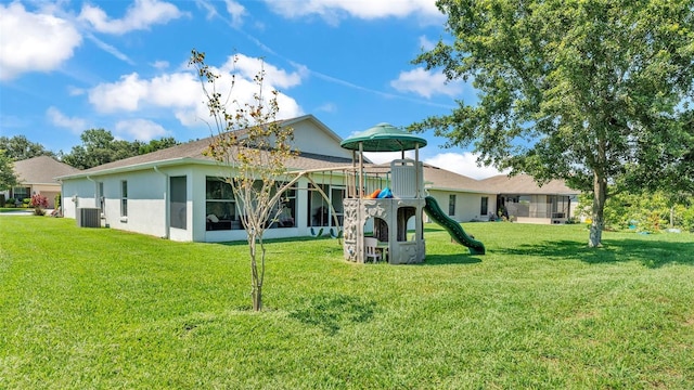 rear view of house with a playground, a yard, and stucco siding