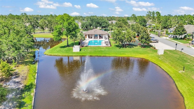 drone / aerial view of a nearby body of water, a pool, and a tree filled landscape