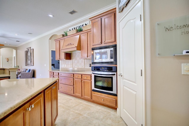 2032 Indian Sky Cir, Lakeland, FL 33813 - kitchen with stainless steel appliances, arched walkways, custom exhaust hood, backsplash, and crown molding