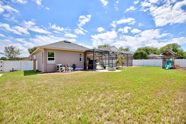 2032 Indian Sky Cir, Lakeland, FL 33813 - back of property featuring a playground, glass enclosure, stucco siding, and a patio