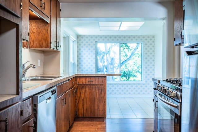 2710 Fairmount Ave, Lakeland, FL 33803 - kitchen with stainless steel appliances, wallpapered walls, a sink, light countertops, and a peninsula