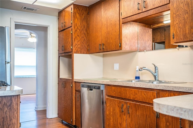 2710 Fairmount Ave, Lakeland, FL 33803 - kitchen with appliances with stainless steel finishes, a sink, light countertops, wood finished floors, and brown cabinetry