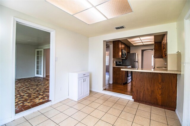 2710 Fairmount Ave, Lakeland, FL 33803 - kitchen featuring range, stainless steel microwave, light countertops, light tile patterned floors, and baseboards