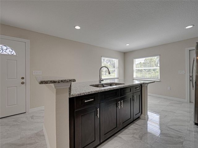 1415 Southern Ave, Lakeland, FL 33803 - kitchen featuring a sink, light marble finish flooring, light stone counters, an island with sink, and recessed lighting