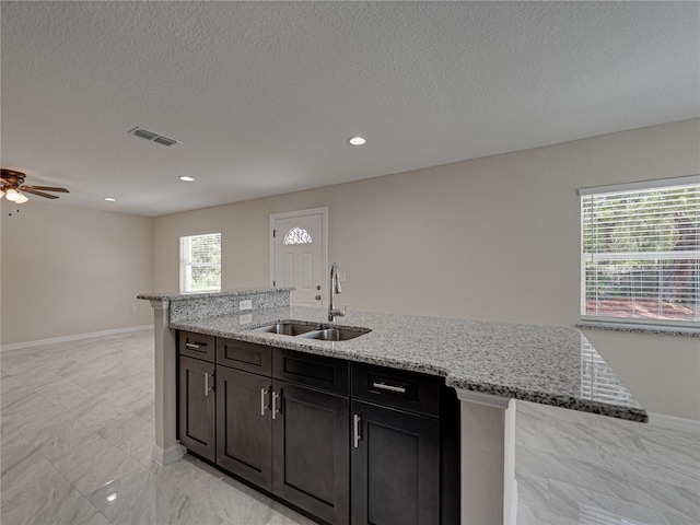 1415 Southern Ave, Lakeland, FL 33803 - kitchen with a sink, a ceiling fan, light stone countertops, baseboards, and an island with sink