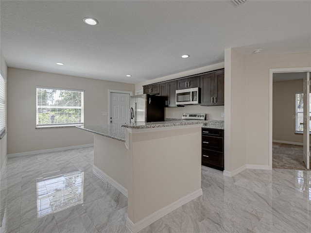 1415 Southern Ave, Lakeland, FL 33803 - kitchen with appliances with stainless steel finishes, light marble finish flooring, baseboards, light stone counters, and a kitchen island with sink
