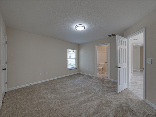 1415 Southern Ave, Lakeland, FL 33803 - unfurnished bedroom with carpet floors, a textured ceiling, baseboards, and ensuite bathroom